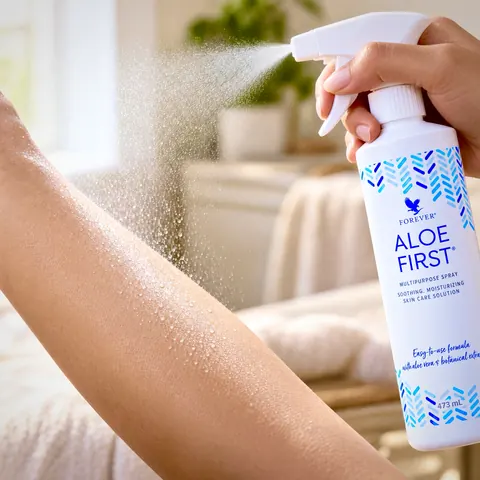 Spray-ul Aloe First pulverizat pe antebraț, cu ceața fină de picături vizibilă pe piele